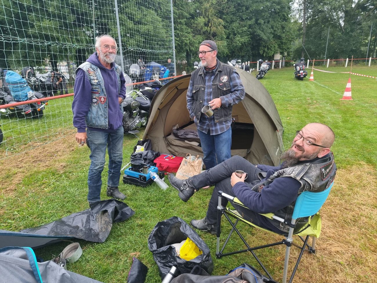 Trois bikers se reposent au camp, l'un dans une chaise pliante