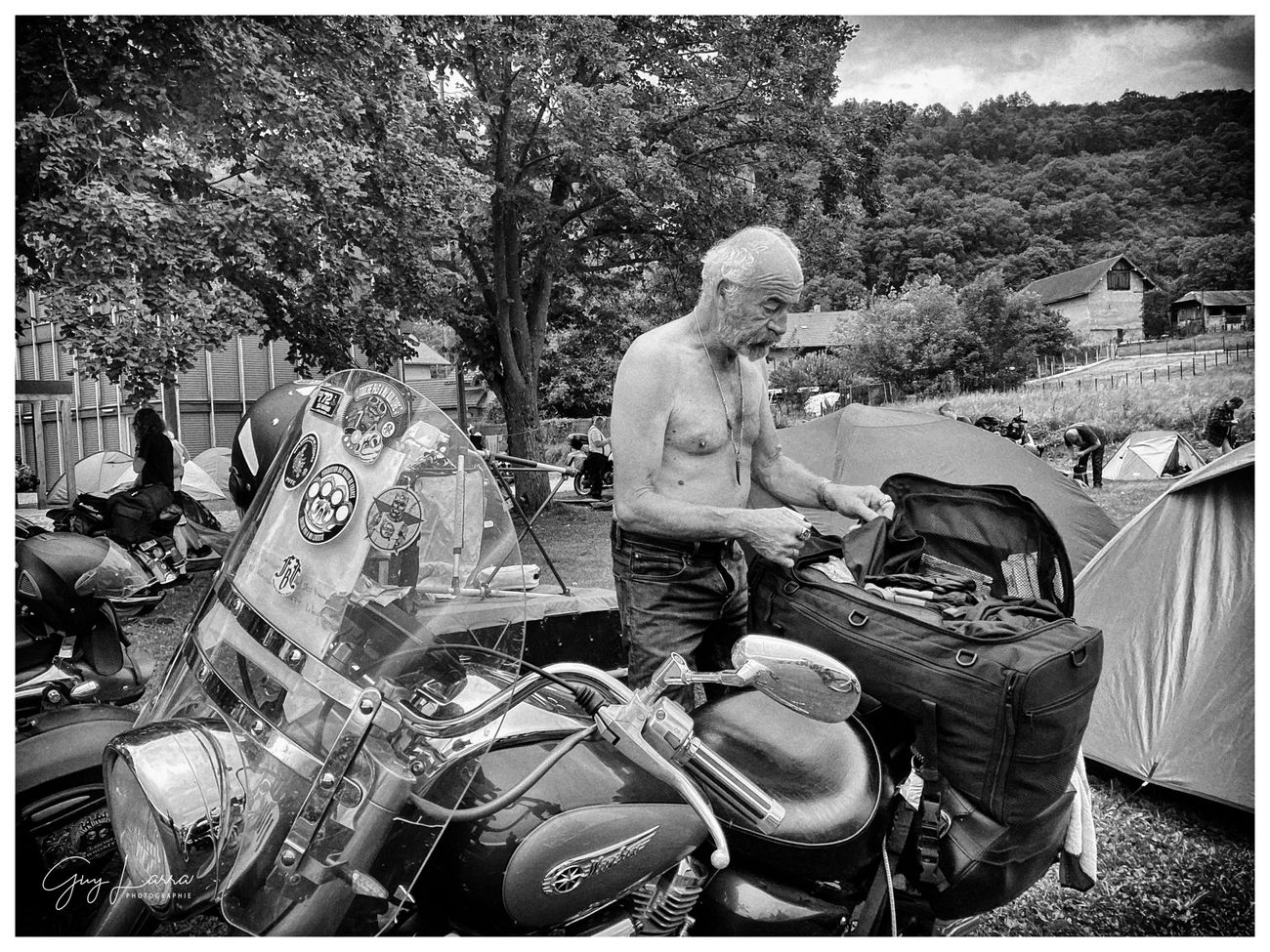 Un biker range son matériel sur sa moto au milieu du camp