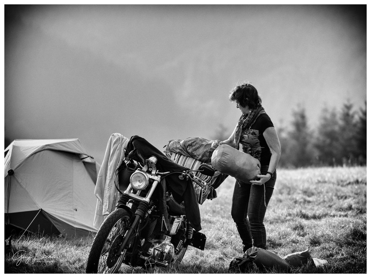 Une bikeuse charge ses bagages sur sa moto au petit matin